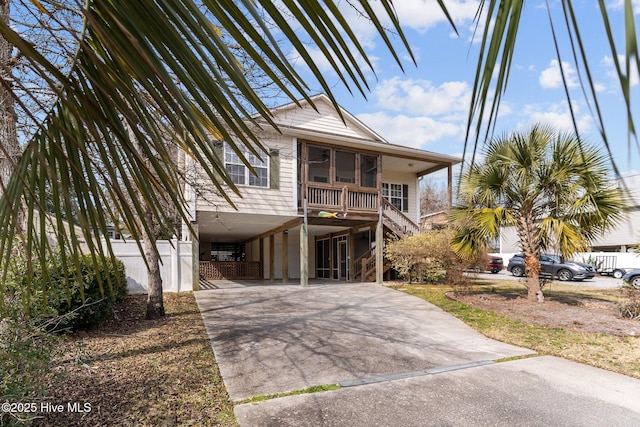 beach home with a carport, a sunroom, driveway, and stairway