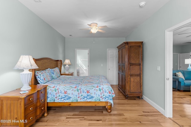 bedroom featuring light wood-type flooring, baseboards, a ceiling fan, and ensuite bathroom