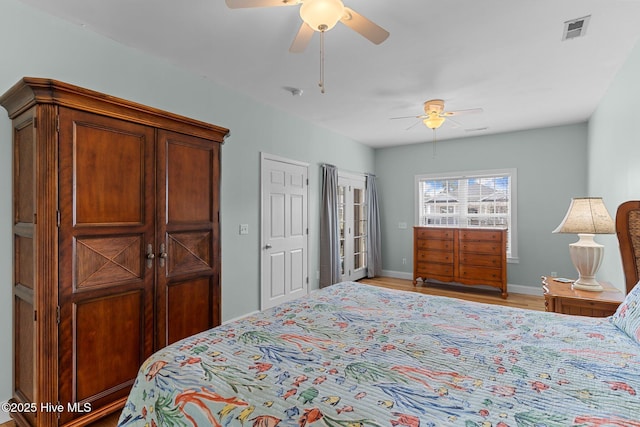 bedroom with ceiling fan, light wood-style flooring, visible vents, and baseboards