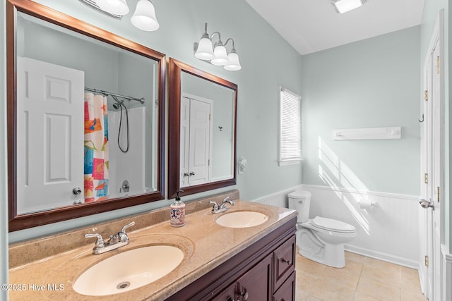 full bath with toilet, double vanity, a sink, and tile patterned floors