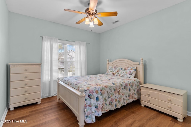 bedroom with ceiling fan, wood finished floors, and visible vents