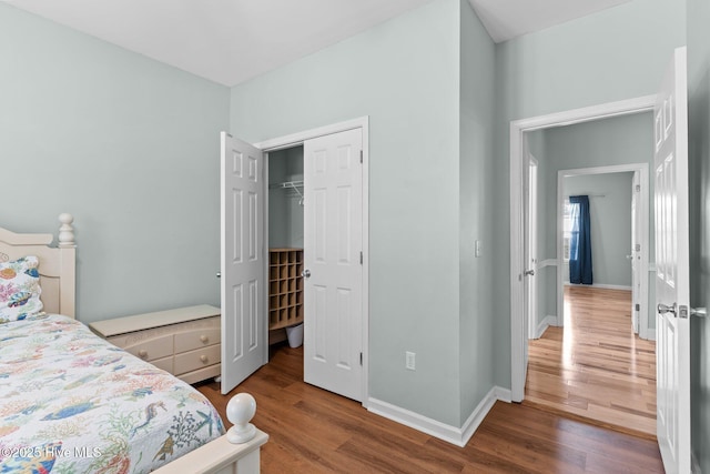 bedroom with a closet, wood finished floors, and baseboards