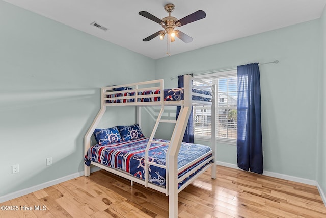 bedroom featuring ceiling fan, wood finished floors, visible vents, and baseboards