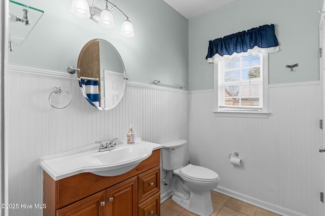 full bath with wainscoting, vanity, toilet, and tile patterned floors