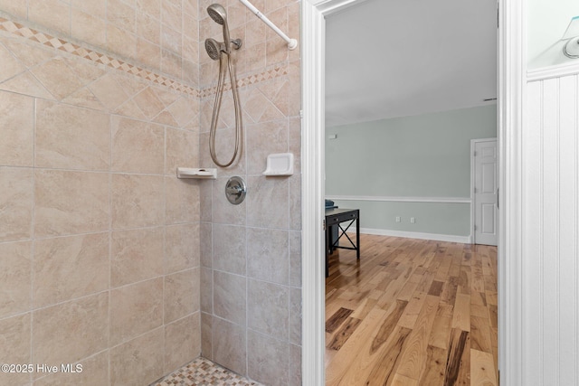 full bathroom with a tile shower and wood finished floors