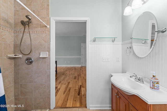 bathroom featuring vanity, a tile shower, and wainscoting