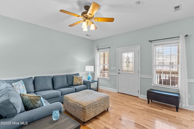 living area featuring ceiling fan, light wood finished floors, visible vents, and baseboards