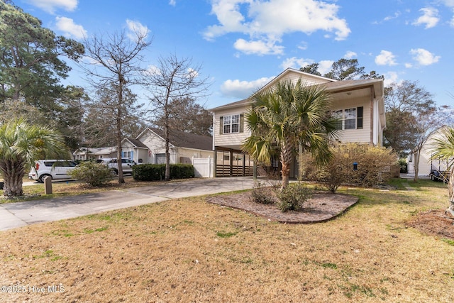 view of front of house with a carport, fence, concrete driveway, and a front yard