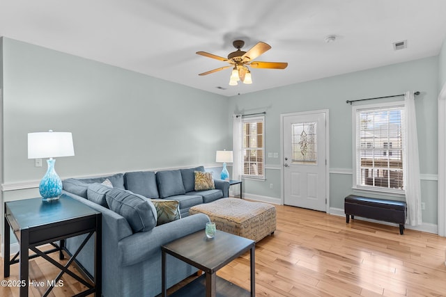 living room with light wood-type flooring, a healthy amount of sunlight, ceiling fan, and visible vents