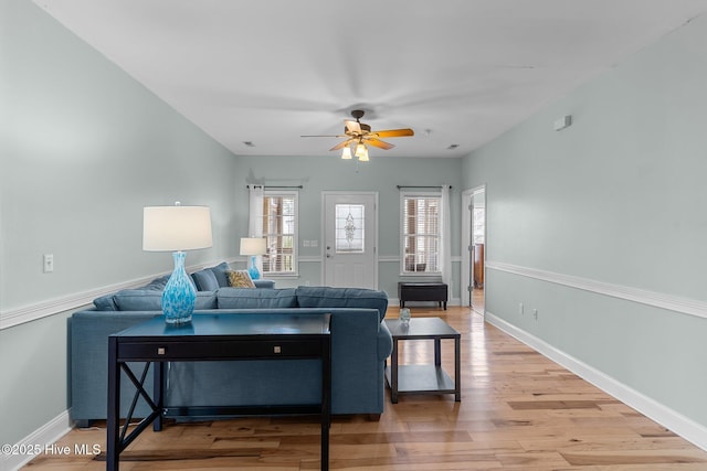 living room featuring a ceiling fan, baseboards, and wood finished floors