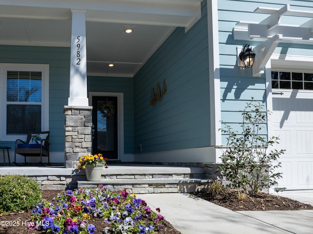 view of exterior entry featuring stone siding and covered porch