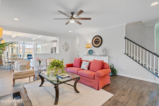 living area featuring stairway, crown molding, ceiling fan, and wood finished floors