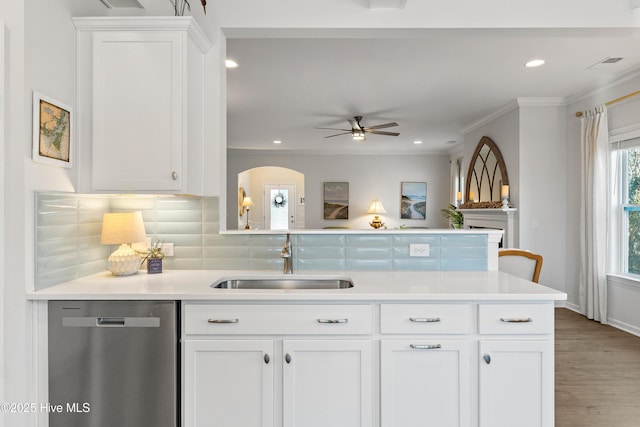 kitchen featuring a sink, white cabinetry, a peninsula, crown molding, and dishwasher