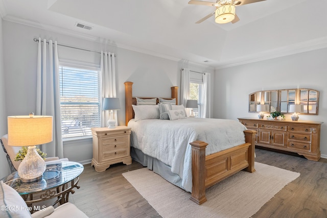 bedroom with a tray ceiling, visible vents, and wood finished floors