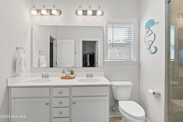 full bath featuring double vanity, a tile shower, toilet, and a sink