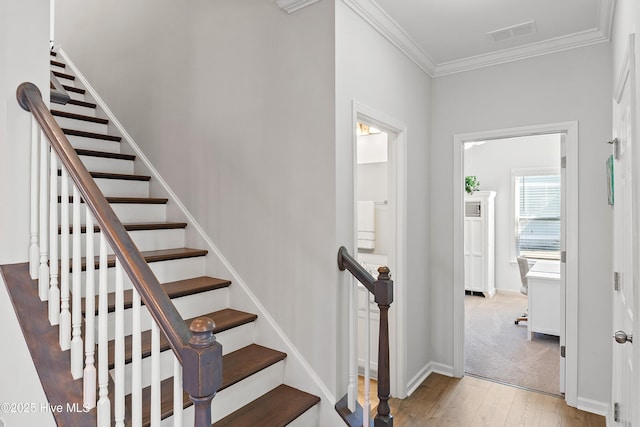 staircase featuring visible vents, wood finished floors, baseboards, and ornamental molding