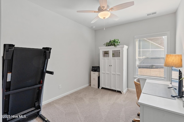 office space with visible vents, light colored carpet, baseboards, and a ceiling fan