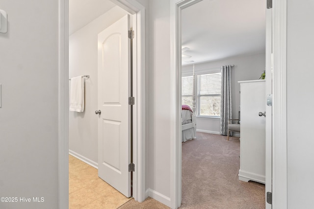 corridor featuring baseboards and light colored carpet