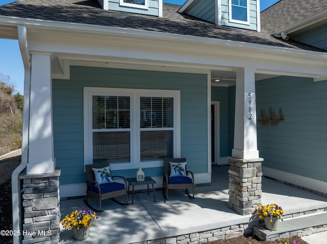 property entrance featuring covered porch and a shingled roof