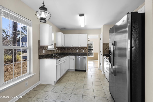 kitchen with stainless steel appliances, decorative backsplash, light tile patterned flooring, a sink, and white cabinetry