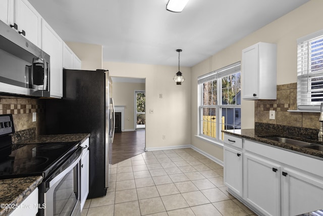 kitchen with light tile patterned flooring, stainless steel appliances, a sink, white cabinetry, and baseboards