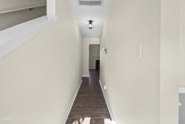 hall with visible vents, baseboards, and wood finished floors