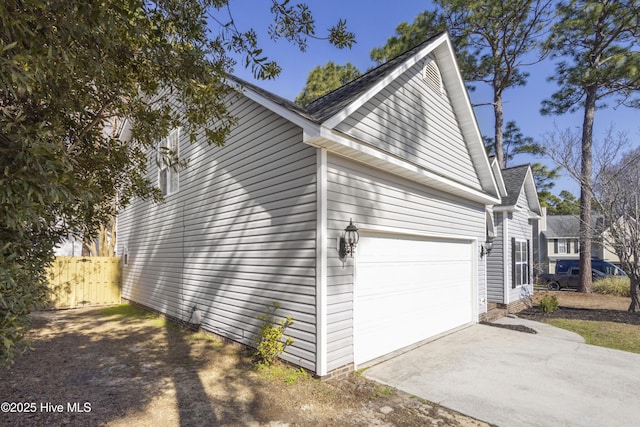 view of side of home featuring concrete driveway, an attached garage, and fence