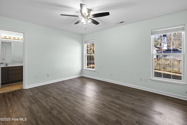 unfurnished bedroom with baseboards, multiple windows, visible vents, and wood finished floors