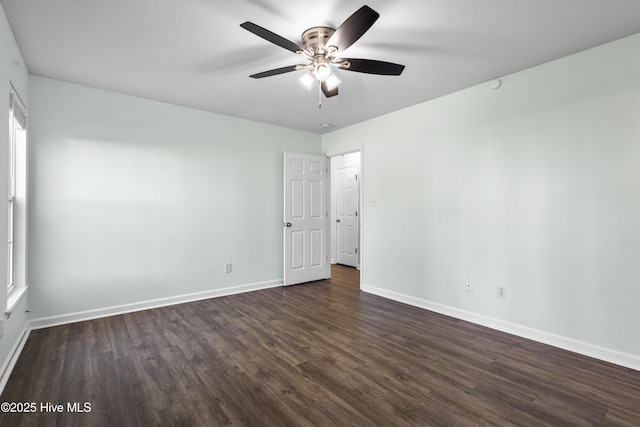 spare room with a ceiling fan, dark wood finished floors, and baseboards