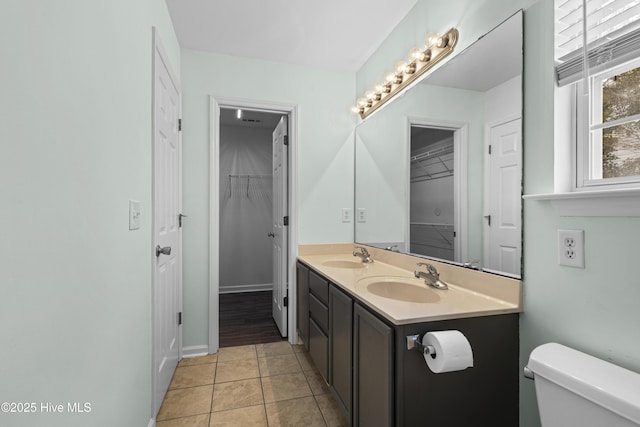 full bath with toilet, tile patterned flooring, double vanity, and a sink