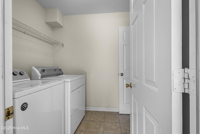 washroom with light tile patterned floors, laundry area, washer and clothes dryer, and baseboards