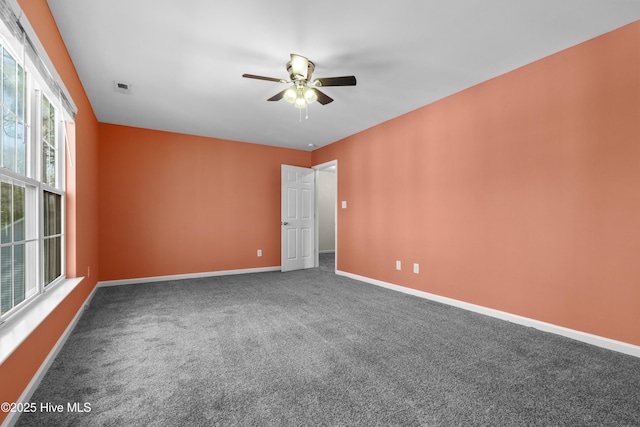 carpeted spare room featuring a ceiling fan, visible vents, and baseboards