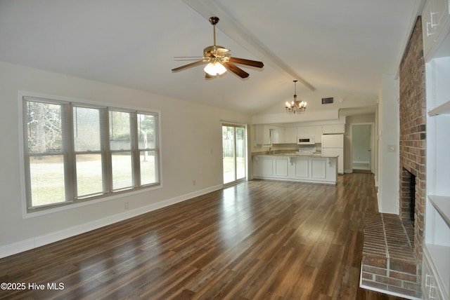 unfurnished living room with visible vents, dark wood finished floors, lofted ceiling with beams, a fireplace, and ceiling fan with notable chandelier