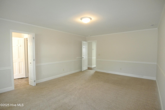 empty room featuring light colored carpet, crown molding, and baseboards