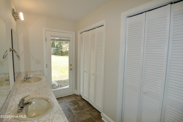 bathroom with a sink, double vanity, stone finish floor, and a closet