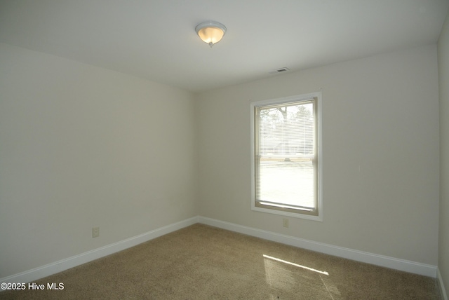 spare room with light carpet, visible vents, and baseboards