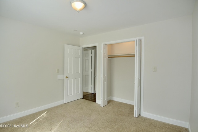 unfurnished bedroom featuring a closet, light carpet, and baseboards