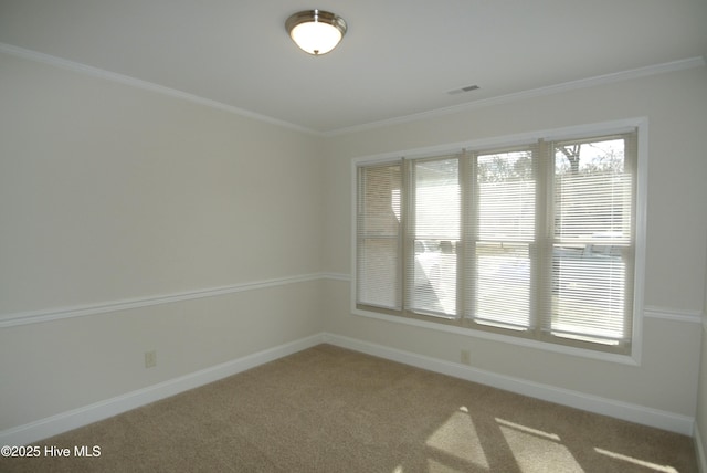 carpeted spare room with visible vents, baseboards, and crown molding