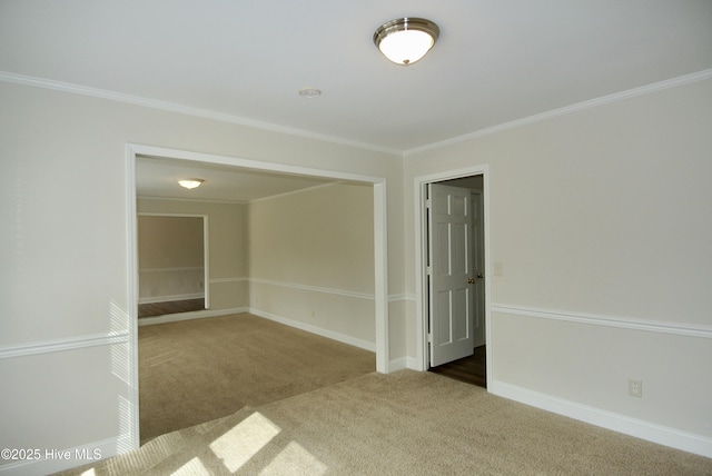 carpeted spare room featuring baseboards and crown molding