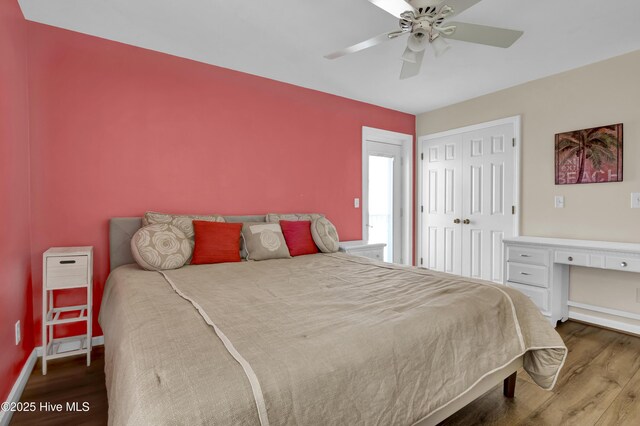 bedroom featuring a closet, a ceiling fan, built in study area, wood finished floors, and baseboards