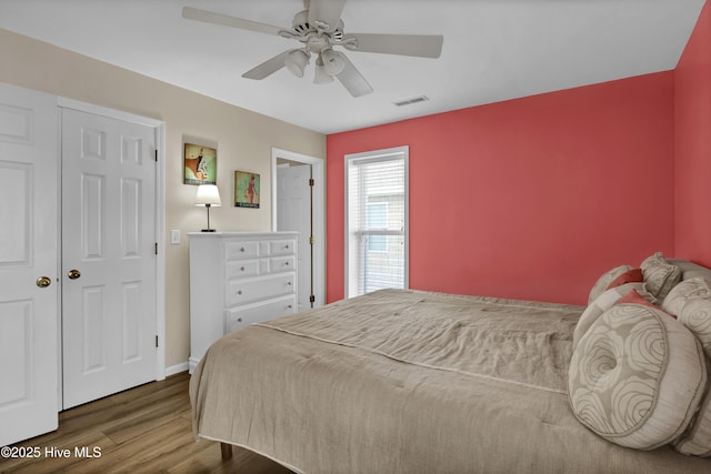 bedroom featuring visible vents, ceiling fan, baseboards, and wood finished floors