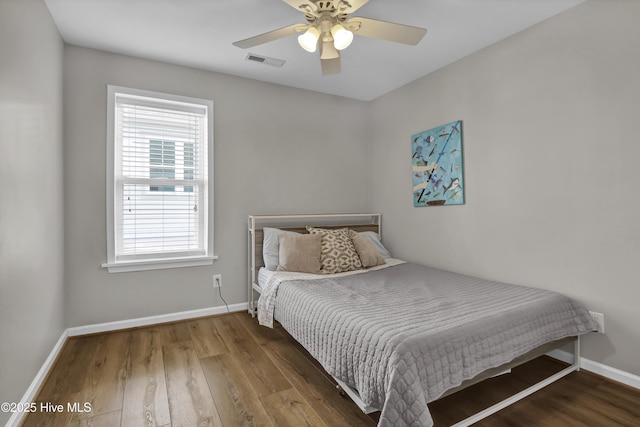 bedroom with visible vents, baseboards, and wood finished floors