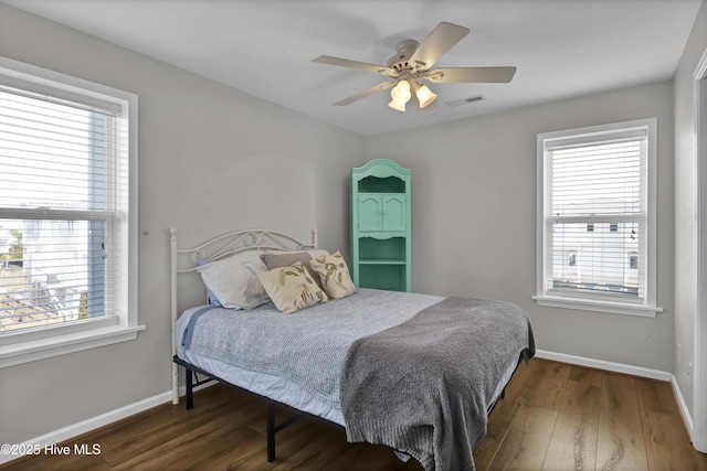 bedroom featuring multiple windows, visible vents, baseboards, and wood finished floors