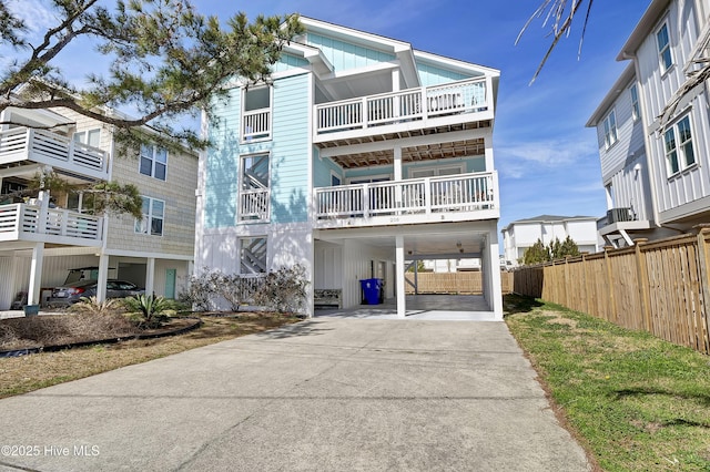 beach home featuring concrete driveway, board and batten siding, and fence