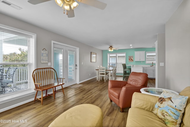 living room featuring plenty of natural light, wood finished floors, visible vents, and baseboards