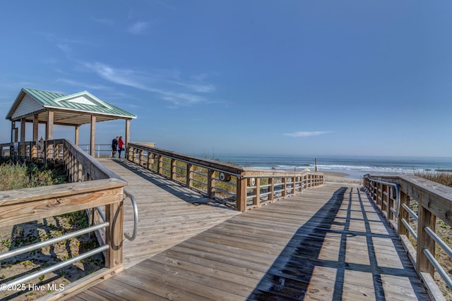 view of dock with a water view, a beach view, and a gazebo