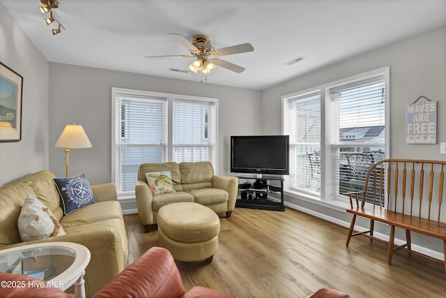 living room featuring baseboards, ceiling fan, visible vents, and wood finished floors