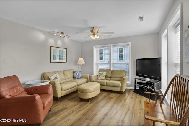 living room featuring a ceiling fan, visible vents, and light wood finished floors