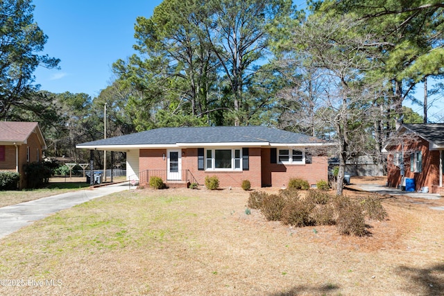 single story home with concrete driveway, an attached carport, fence, a front yard, and brick siding