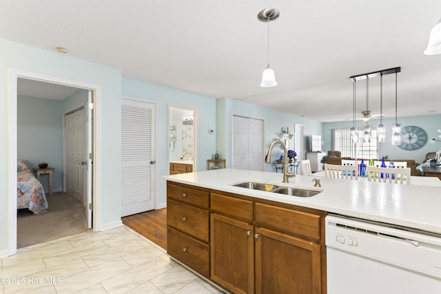 kitchen with hanging light fixtures, a sink, brown cabinets, and white dishwasher